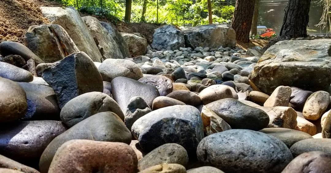 Creek bed drainage installation with boulders and river stone